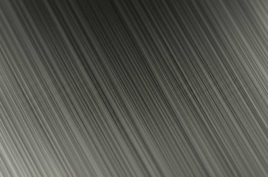 A close-up shot showing light grazing across the textured, glossy surface of a metal art print, highlighting its depth and vibrant color.