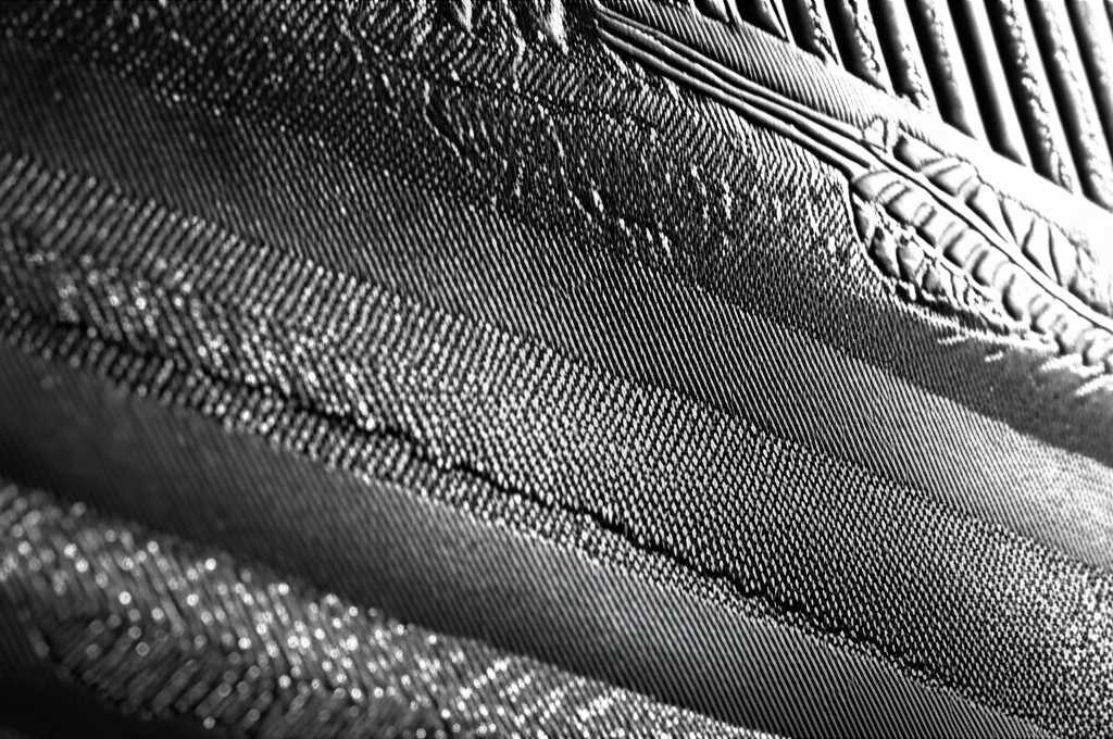 Close-up side view of a textured metal print showing light interacting with its glossy surface.