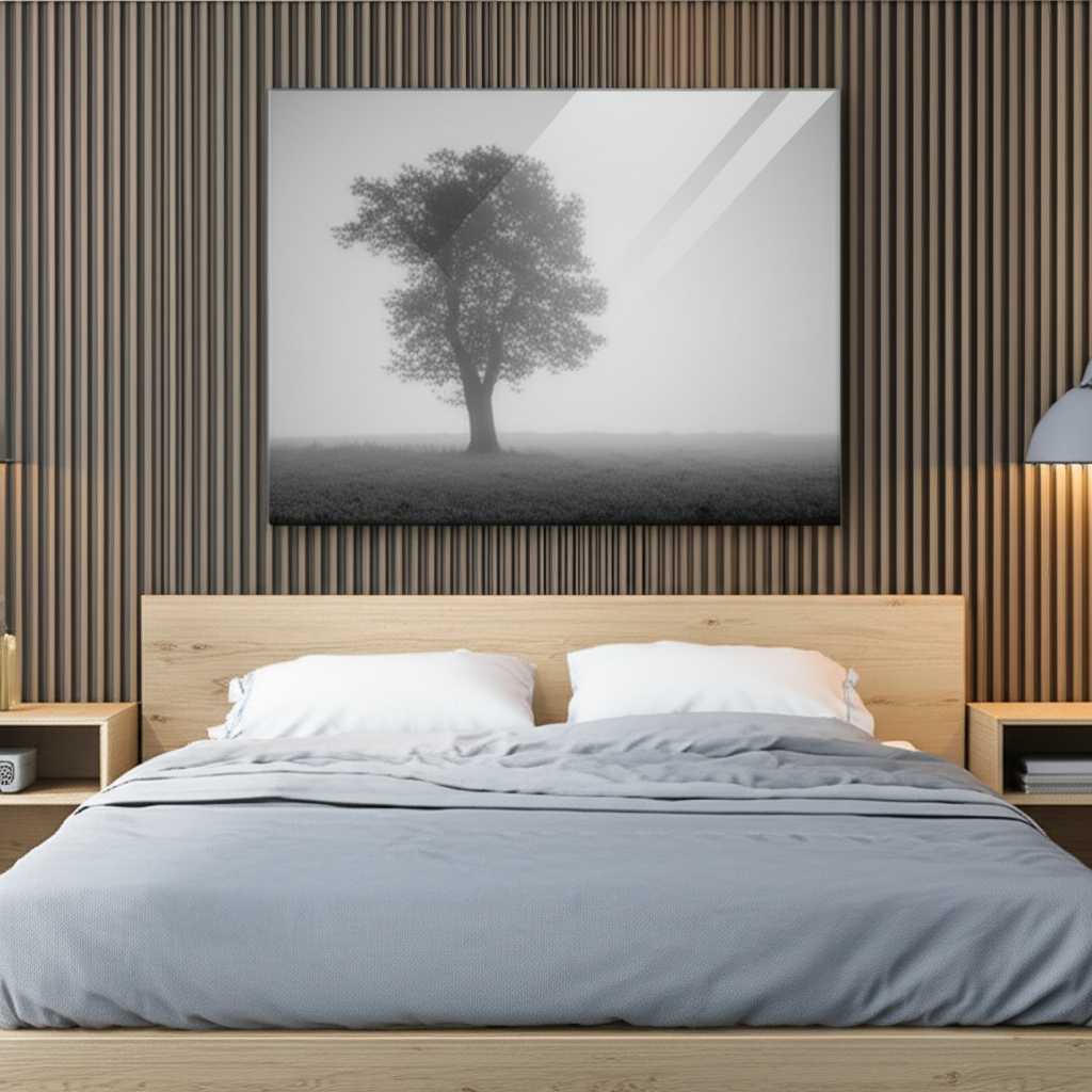 A serene bedroom with a large metal print of a minimalist black-and-white photograph of a lone tree, hung above a neatly made bed with neutral-colored linens.