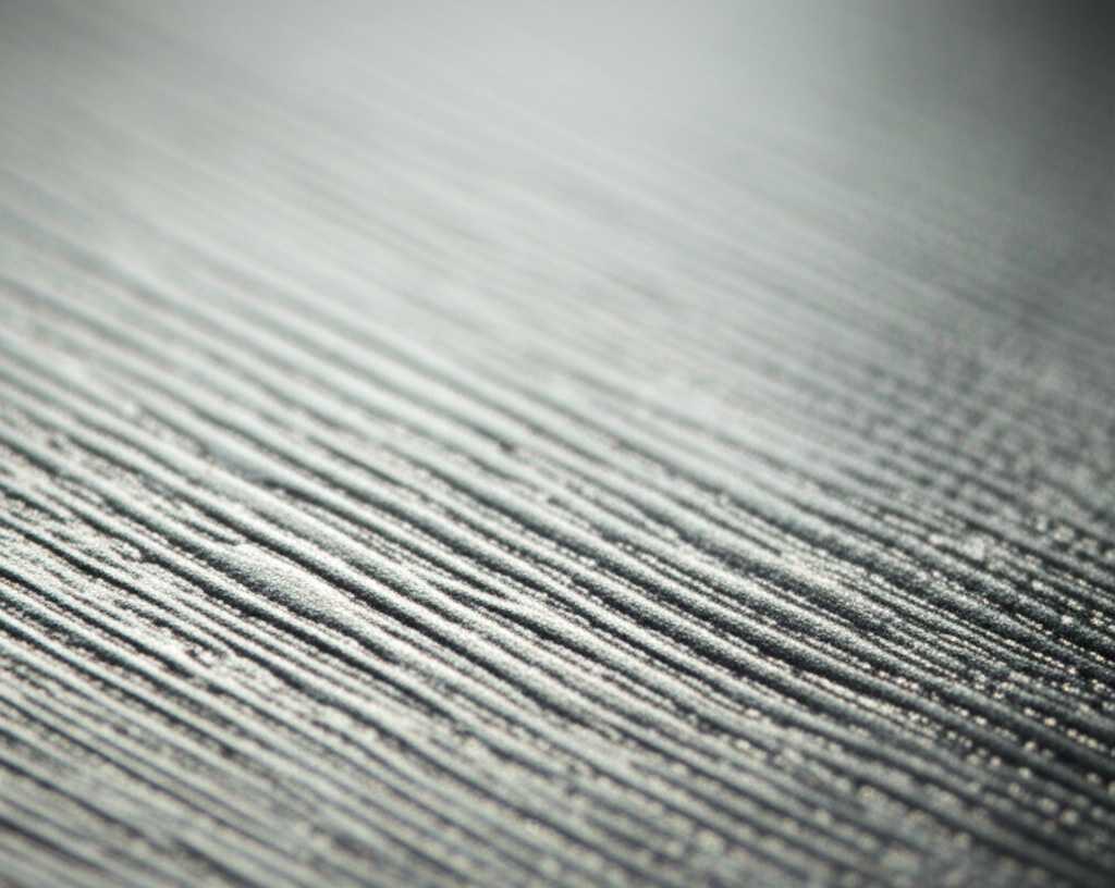 Abstract close-up concept image showing light reflecting off a subtly textured and highly glossy metallic surface, hinting at layers and depth, with vibrant colors.