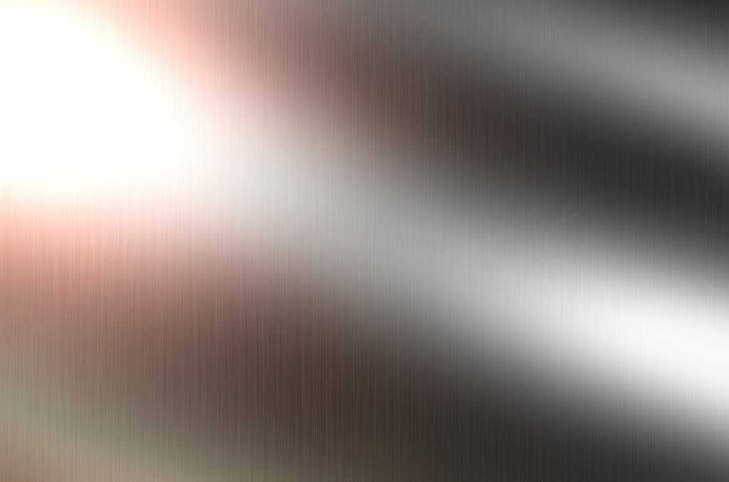 Abstract close-up of light reflecting off a subtly textured, glossy metal surface, showcasing a spectrum of rich colors and a sense of depth.