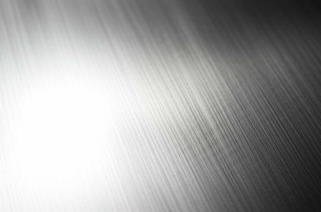 Close-up conceptual shot of light reflecting off a textured, glossy metal surface, hinting at abstract art.