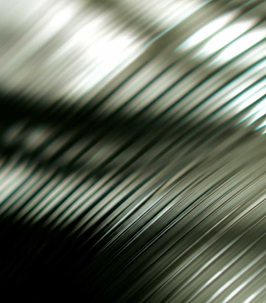 Close-up conceptual image illustrating the idea of light interacting with a textured and glossy metal surface, showcasing abstract plays of light and shadow to represent depth and vibrancy.