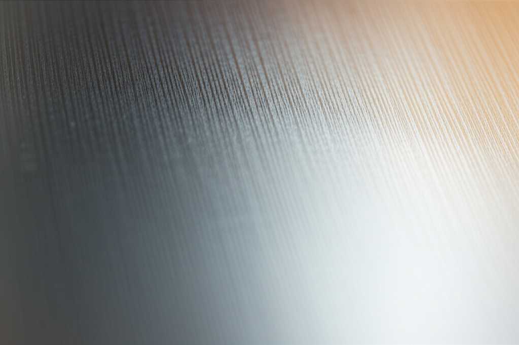 A close-up perspective of light subtly reflecting off the glossy surface of a metal art piece, highlighting its texture.