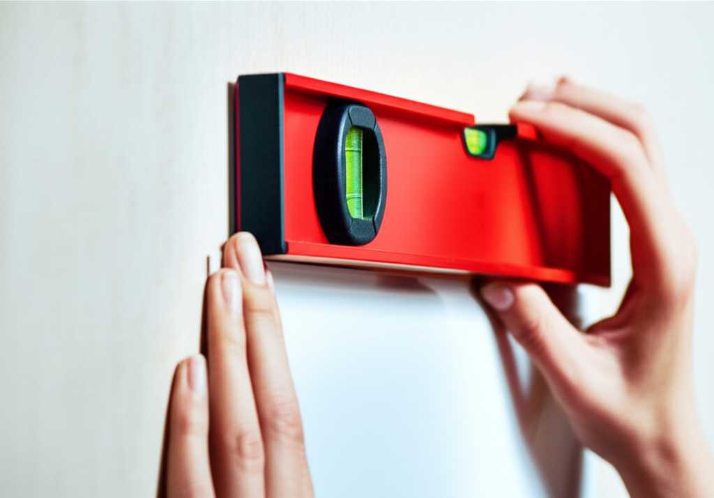 Hands carefully using a level to align a sleek metal print on a clean, modern wall